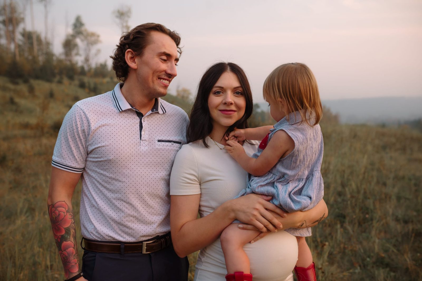 Russell, Wacey, and their daughter in a golden field at dusk