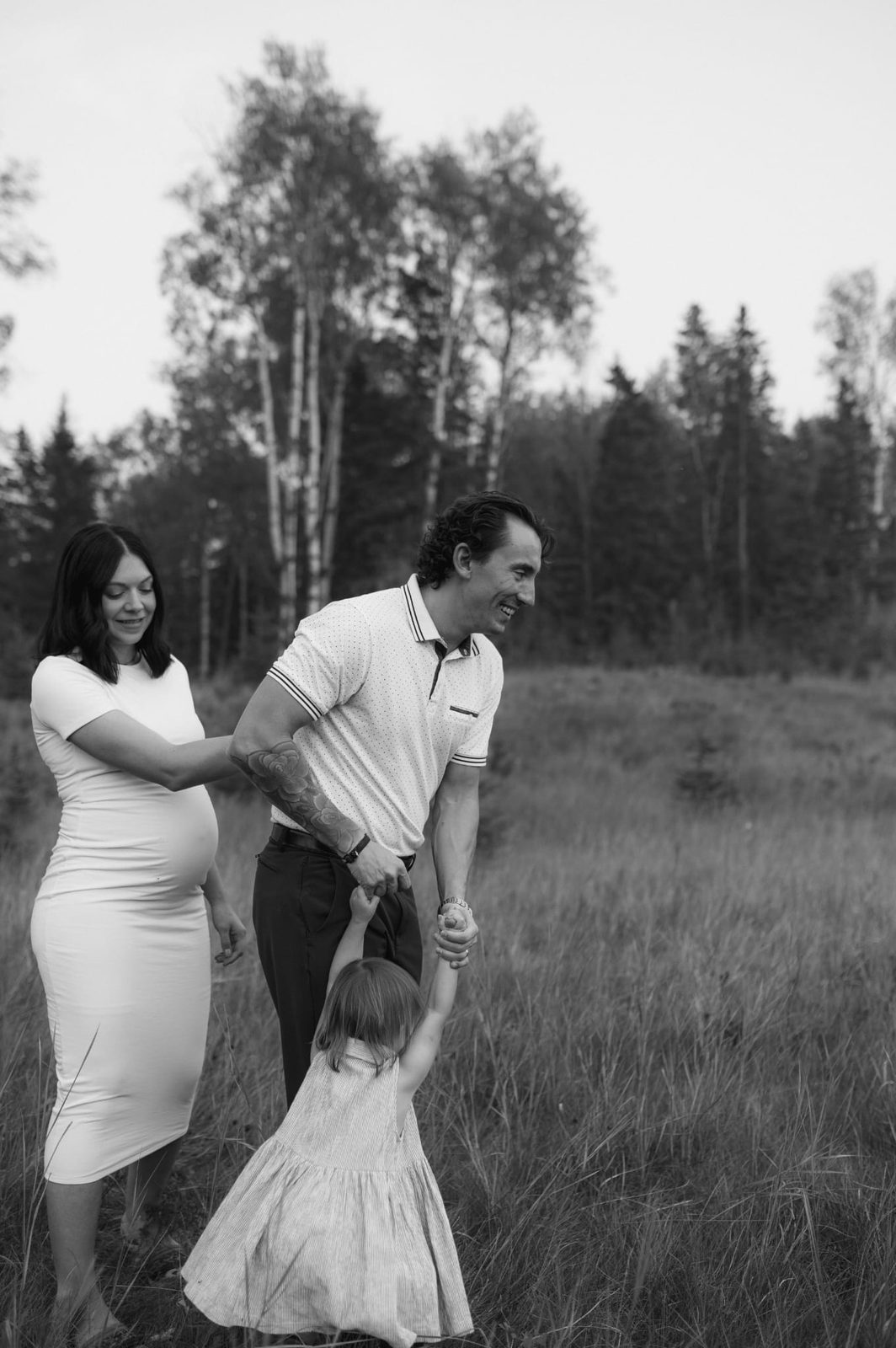 Russell spinning his daughter in a grassy field while Wacey watches