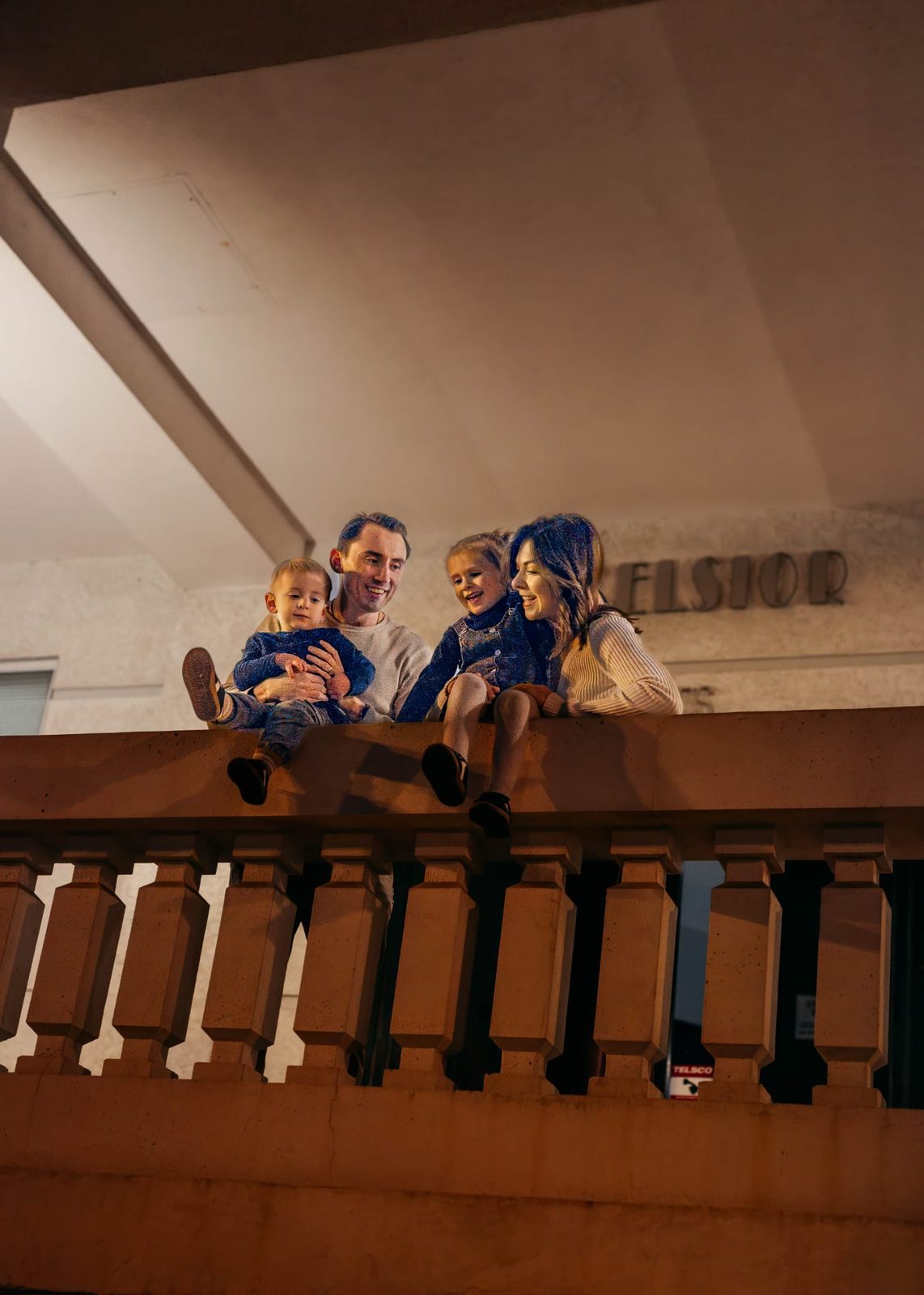 The family sitting together on a balcony ledge at night