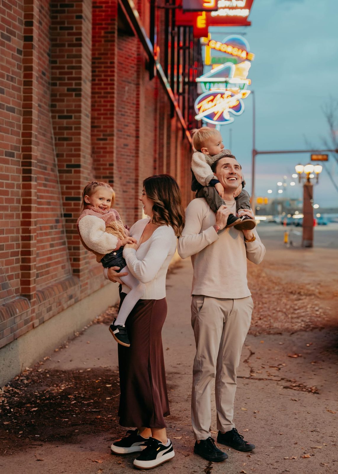 The family walking together on a neon-lit street at dusk